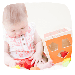 Baby spielt mit einem Steckwürfel aus Holz