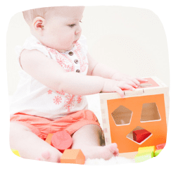 Baby spielt mit einem Steckwürfel aus Holz